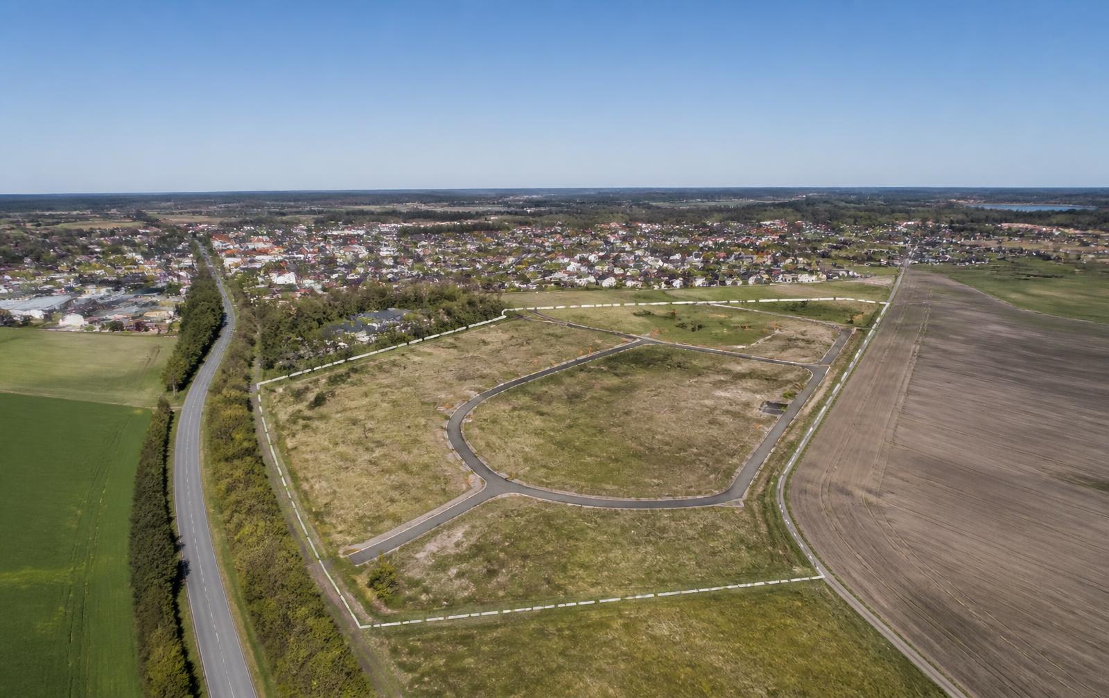 Flygbild över obebyggd mark intill en svensk tätort